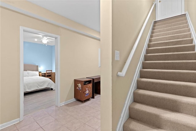 staircase with tile patterned flooring, a ceiling fan, and baseboards