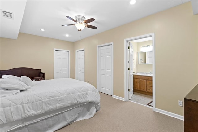 bedroom featuring visible vents, baseboards, multiple closets, light colored carpet, and recessed lighting