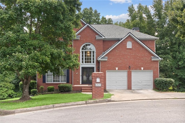 traditional-style home with concrete driveway, french doors, and brick siding