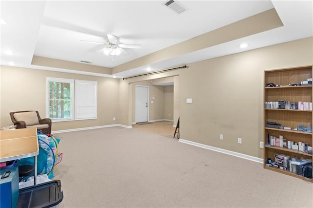 living area featuring a raised ceiling, baseboards, visible vents, and ceiling fan