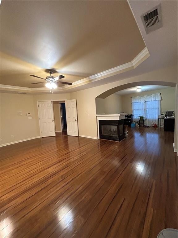 unfurnished living room featuring visible vents, a glass covered fireplace, hardwood / wood-style floors, arched walkways, and ceiling fan