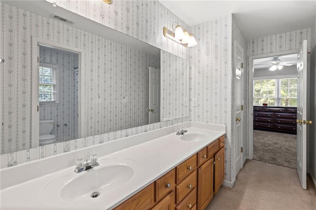 bathroom with double vanity, visible vents, wallpapered walls, and a sink