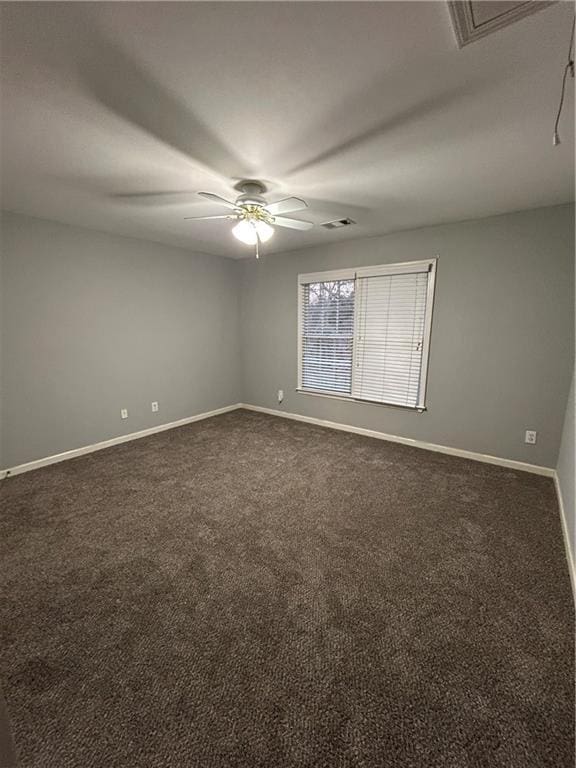 spare room with dark colored carpet, visible vents, baseboards, and ceiling fan