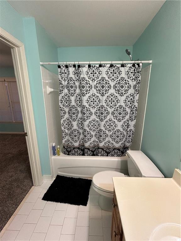 full bathroom featuring tile patterned floors, vanity, toilet, and shower / tub combo with curtain