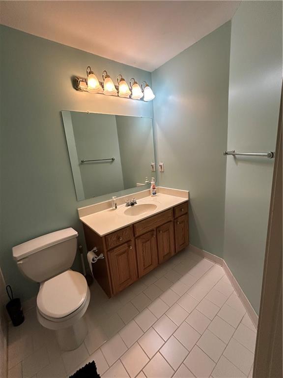 bathroom featuring vanity, toilet, baseboards, and tile patterned flooring