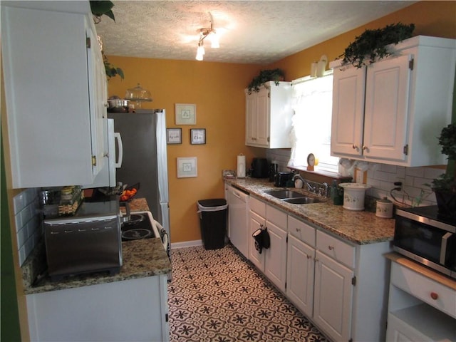 274 Griffith St, Winder, GA 30680 - kitchen featuring appliances with stainless steel finishes, a sink, white cabinetry, decorative backsplash, and a textured ceiling