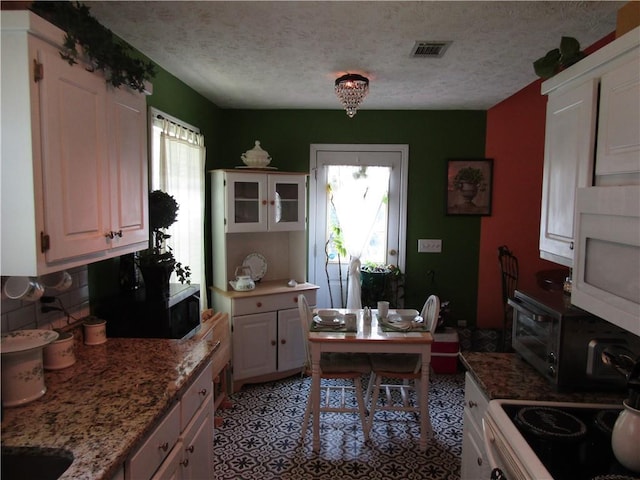 274 Griffith St, Winder, GA 30680 - kitchen featuring white microwave, range, stainless steel microwave, a textured ceiling, and decorative backsplash