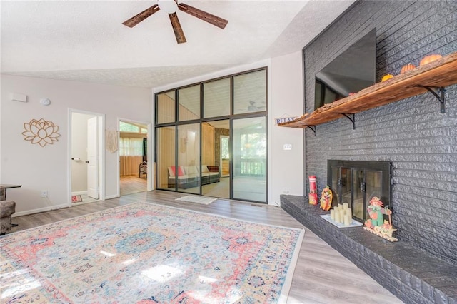 1019 Whippoorwill Rd, Monticello, GA 31064 - unfurnished living room featuring a ceiling fan, wood finished floors, a brick fireplace, lofted ceiling, and a textured ceiling