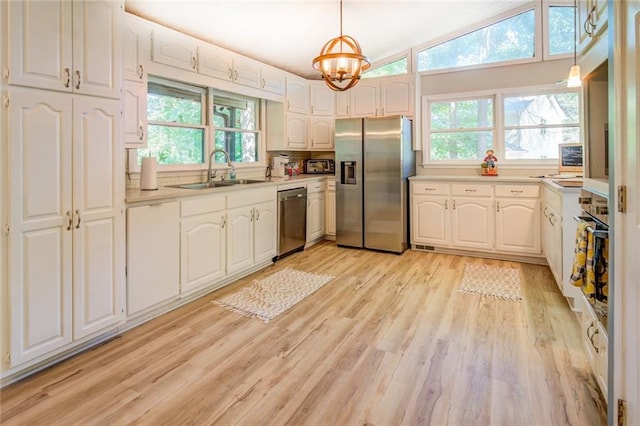 1019 Whippoorwill Rd, Monticello, GA 31064 - kitchen with stainless steel appliances, light wood-type flooring, white cabinets, light countertops, and a chandelier