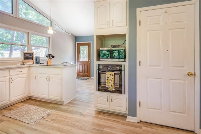 1019 Whippoorwill Rd, Monticello, GA 31064 - kitchen featuring appliances with stainless steel finishes, white cabinetry, light wood-type flooring, vaulted ceiling, and pendant lighting