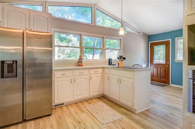1019 Whippoorwill Rd, Monticello, GA 31064 - kitchen with stainless steel refrigerator with ice dispenser, light wood finished floors, vaulted ceiling, white cabinetry, and hanging light fixtures