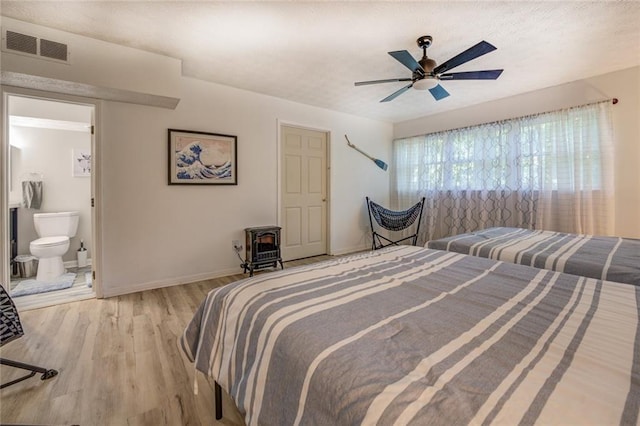 1019 Whippoorwill Rd, Monticello, GA 31064 - bedroom with light wood finished floors, a wood stove, ceiling fan, and ensuite bathroom