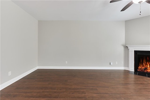 unfurnished living room featuring dark wood-type flooring and ceiling fan