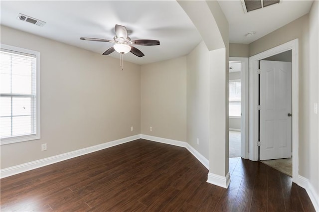 empty room with ceiling fan, a healthy amount of sunlight, and dark hardwood / wood-style floors