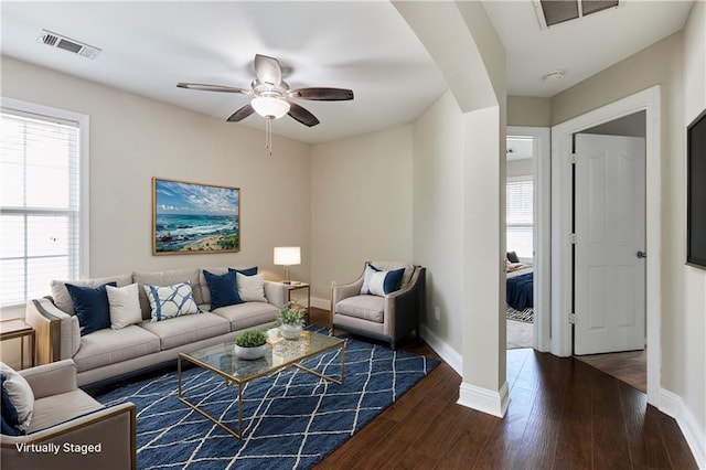 living room featuring dark wood-type flooring and ceiling fan