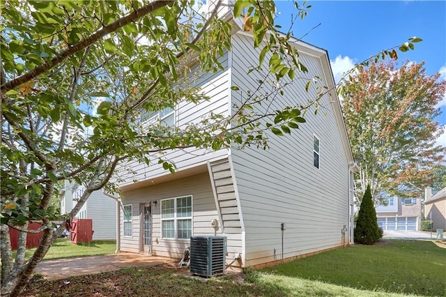 view of side of property featuring central AC unit, a yard, and a patio area