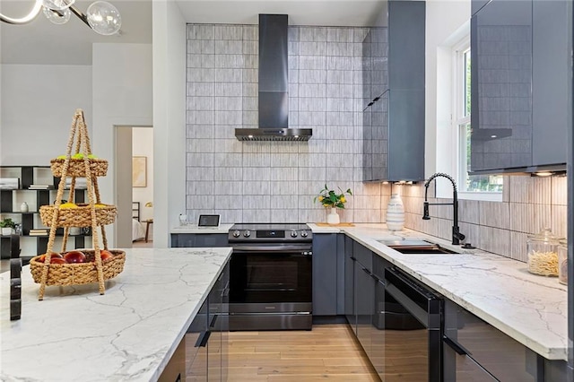 kitchen featuring stainless steel range with electric cooktop, tasteful backsplash, wall chimney range hood, light stone counters, and sink