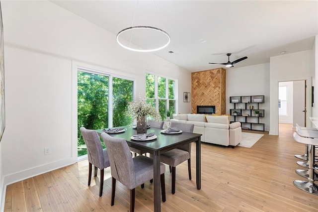 dining room with ceiling fan, light wood-type flooring, and a tile fireplace