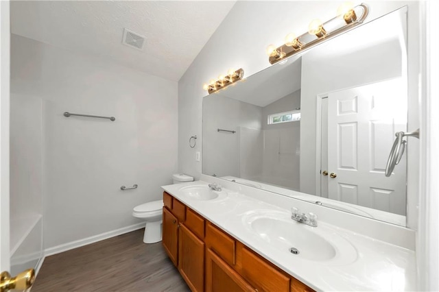 bathroom with wood-type flooring, vanity, toilet, and vaulted ceiling