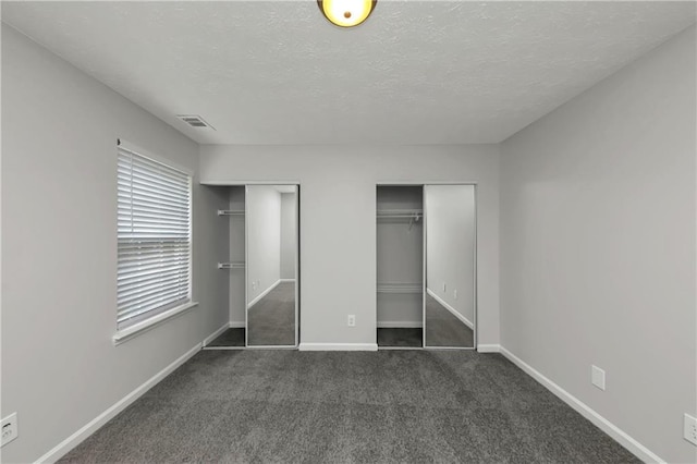 unfurnished bedroom with dark colored carpet and a textured ceiling