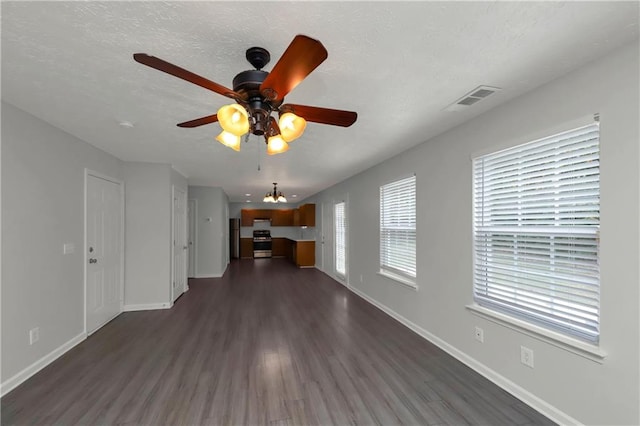 unfurnished living room featuring ceiling fan with notable chandelier, a textured ceiling, and dark hardwood / wood-style flooring