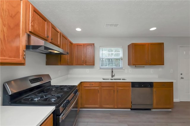 kitchen with a textured ceiling, appliances with stainless steel finishes, wood-type flooring, and sink