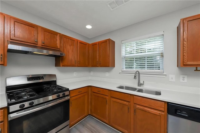 kitchen with appliances with stainless steel finishes, sink, and light hardwood / wood-style flooring