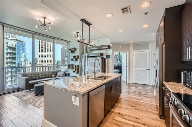 kitchen featuring light wood finished floors, visible vents, a notable chandelier, stainless steel appliances, and a sink