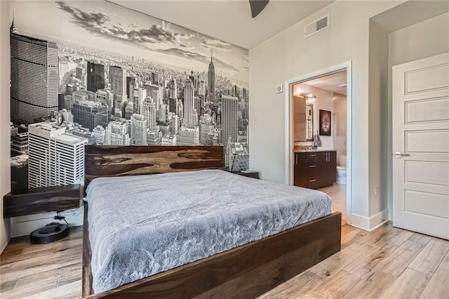 bedroom featuring visible vents, ceiling fan, baseboards, ensuite bathroom, and wood finished floors