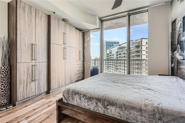 bedroom featuring a ceiling fan, access to outside, light wood-style floors, and expansive windows