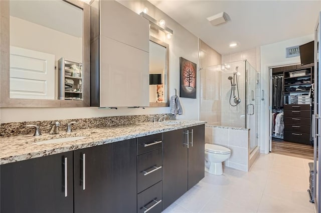 bathroom with tile patterned floors, toilet, a sink, a shower stall, and double vanity