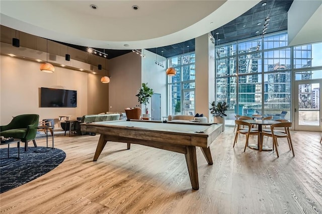 rec room featuring floor to ceiling windows, pool table, a high ceiling, and wood finished floors