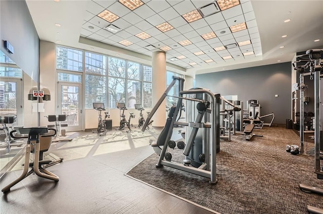 workout area with baseboards, a raised ceiling, a high ceiling, and visible vents