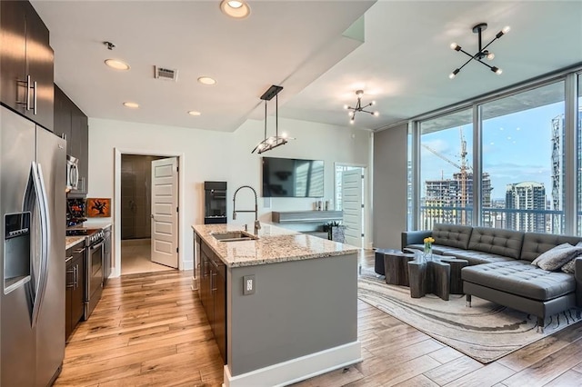 kitchen with visible vents, light wood-type flooring, a sink, appliances with stainless steel finishes, and open floor plan