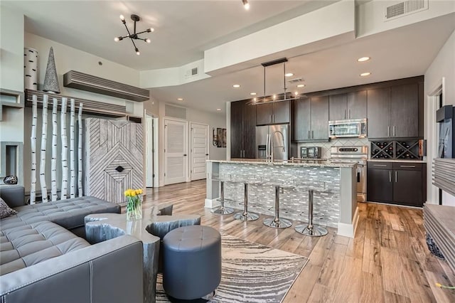 living room with light wood-style flooring, recessed lighting, visible vents, and a chandelier