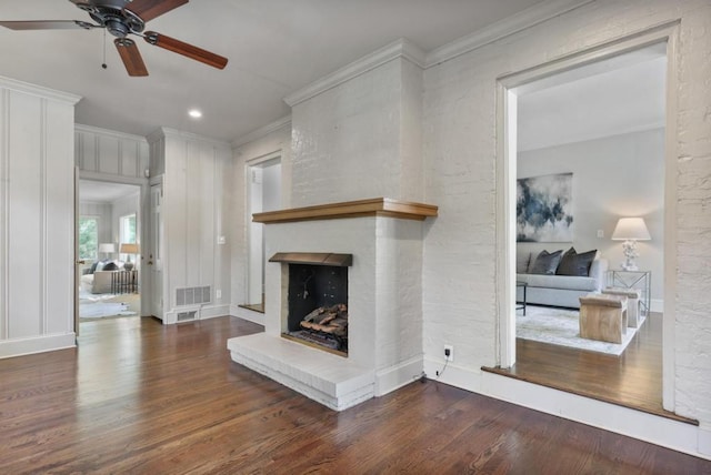 living room featuring dark hardwood / wood-style flooring, a large fireplace, and crown molding