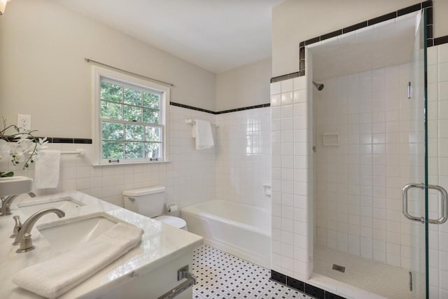 bathroom with vanity, toilet, tile walls, and a tile shower