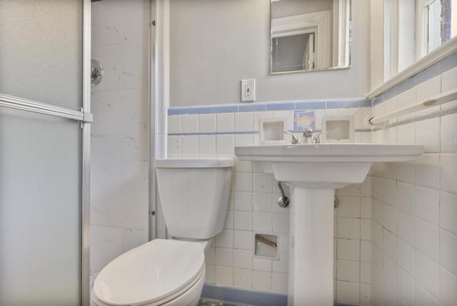 bathroom with tile walls and toilet