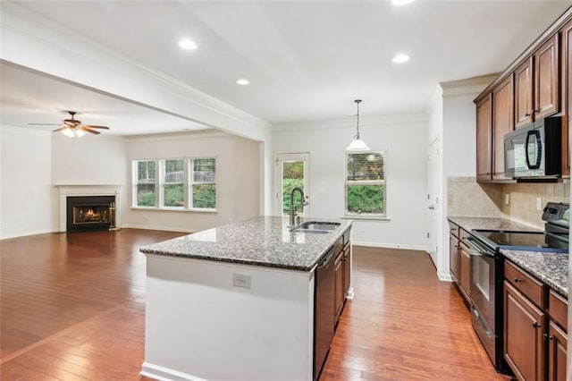 kitchen with sink, dark hardwood / wood-style flooring, pendant lighting, a center island with sink, and black appliances