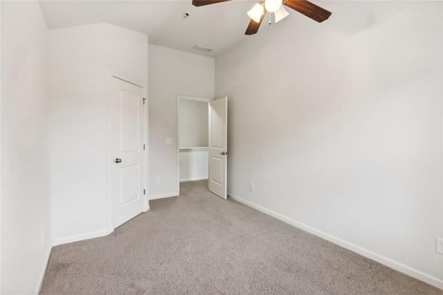 unfurnished bedroom featuring ceiling fan, a closet, light carpet, and vaulted ceiling