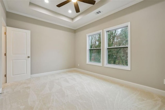 carpeted spare room featuring ceiling fan, ornamental molding, and a tray ceiling