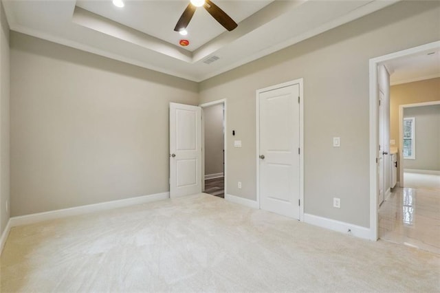 unfurnished bedroom with light colored carpet, a raised ceiling, ceiling fan, and ornamental molding