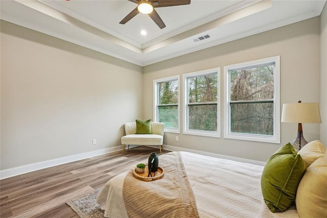 bedroom with ceiling fan, light hardwood / wood-style floors, a raised ceiling, and crown molding