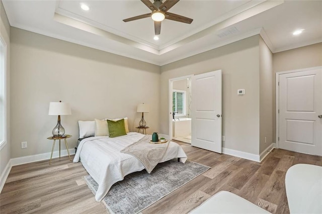 bedroom with ensuite bath, ornamental molding, a raised ceiling, ceiling fan, and light hardwood / wood-style flooring