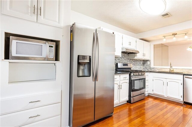 2901 Lenox Way NE Unit 902, Atlanta, GA 30324 - kitchen featuring stainless steel appliances, a sink, under cabinet range hood, white cabinetry, and light wood finished floors