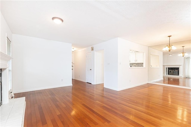 2901 Lenox Way NE Unit 902, Atlanta, GA 30324 - unfurnished living room featuring a glass covered fireplace, light wood-style flooring, baseboards, and a chandelier