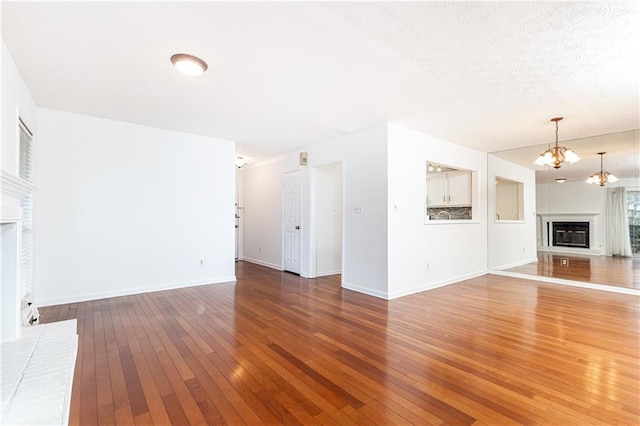 2901 Lenox Way NE Unit 902, Atlanta, GA 30324 - unfurnished living room featuring a glass covered fireplace, hardwood / wood-style flooring, a chandelier, and baseboards