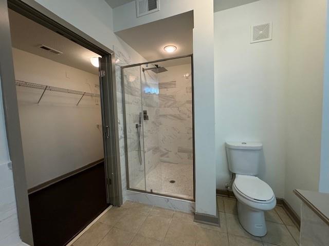 bathroom featuring visible vents, tile patterned flooring, a shower stall, and toilet