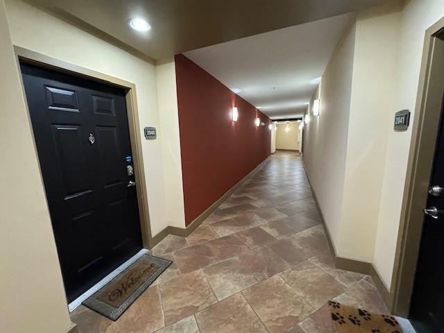 corridor featuring stone finish flooring and baseboards