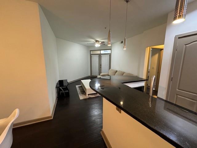 kitchen with dark wood-style floors, dark countertops, a ceiling fan, baseboards, and pendant lighting